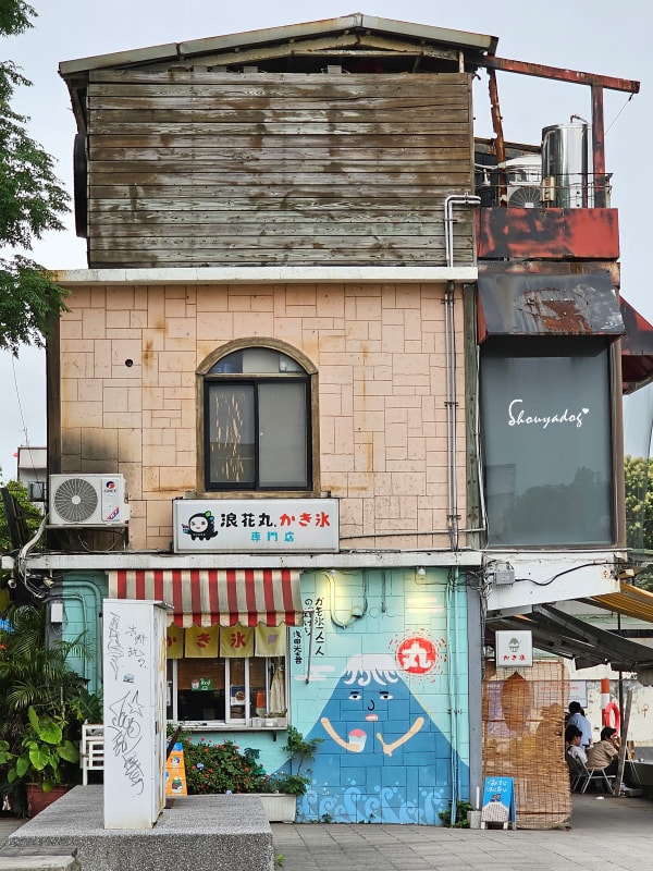 淡水老街美食|朝日夫婦沖繩風日式刨冰:滬尾漁港畔的微醺淡水霞光與藍莓優格,冰晶與淋醬合而為一的琴瑟和鳴✨ - 第5張圖 淡水冰店塗鴉牆面